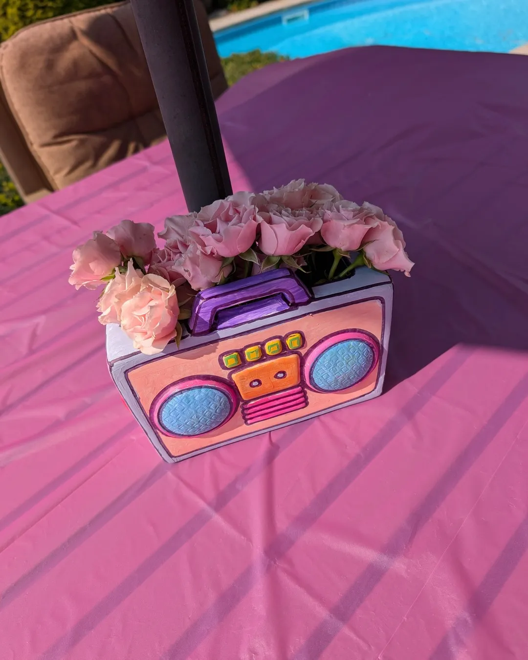 Pink boombox-shaped centrepiece filled with blush roses on a pink tablecloth