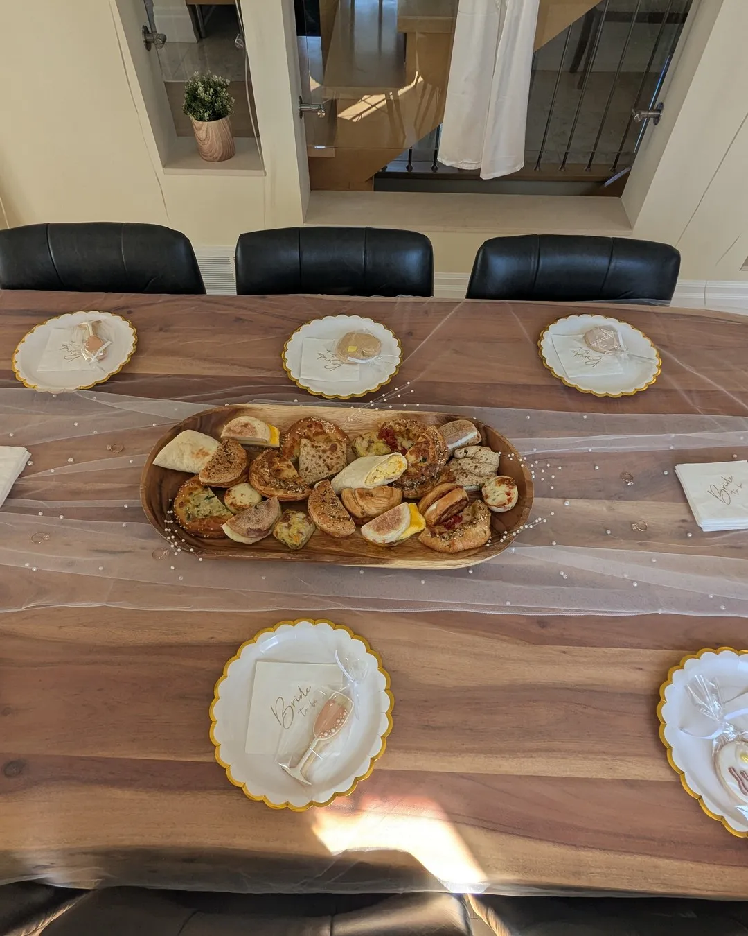 Wooden table set with gold-rimmed plates and a tray of pastries