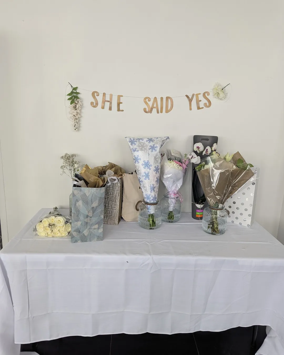 Gift table in white linen under a gold "She said yes" banner