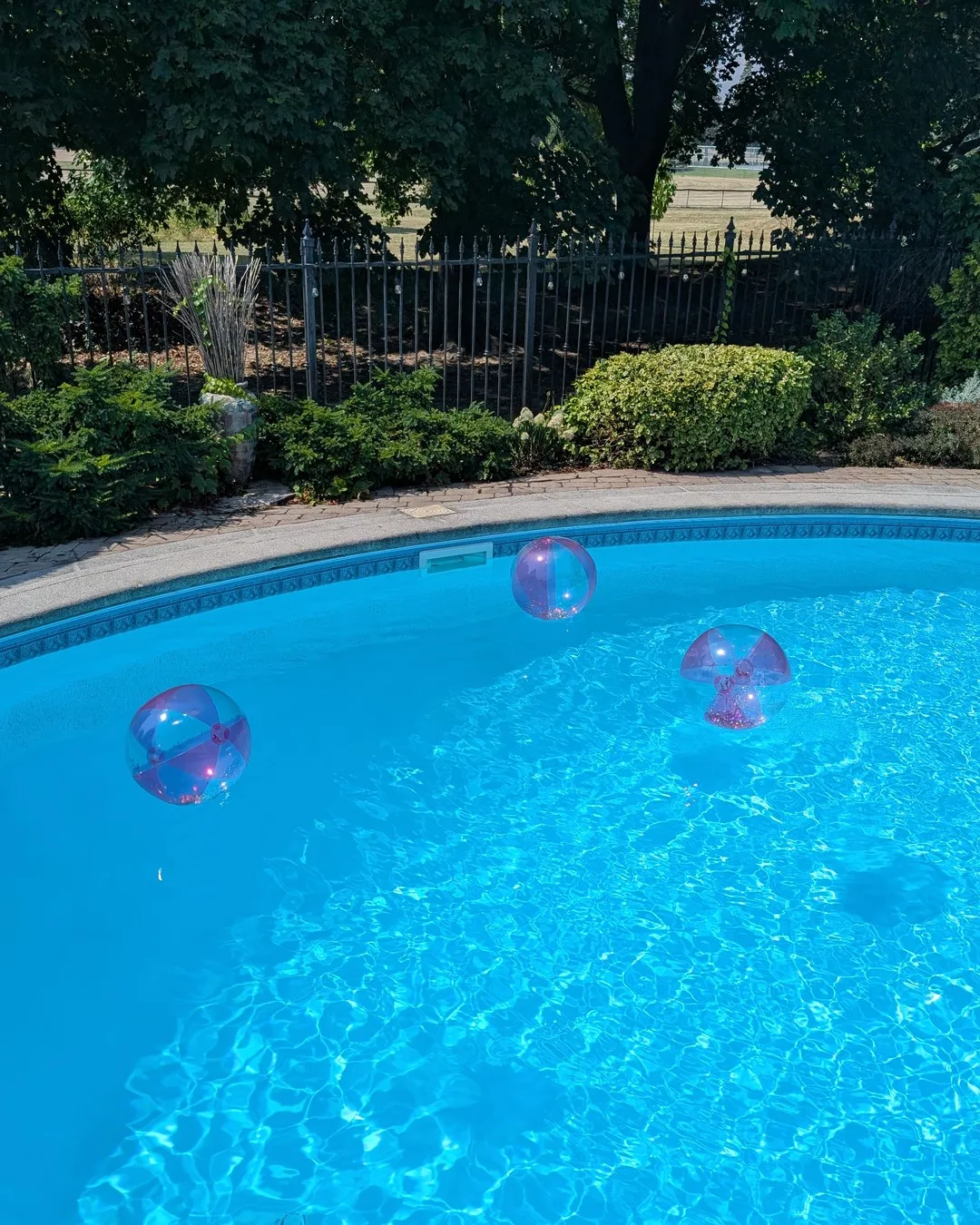 Backyard pool with clear glitter balloons floating on the water