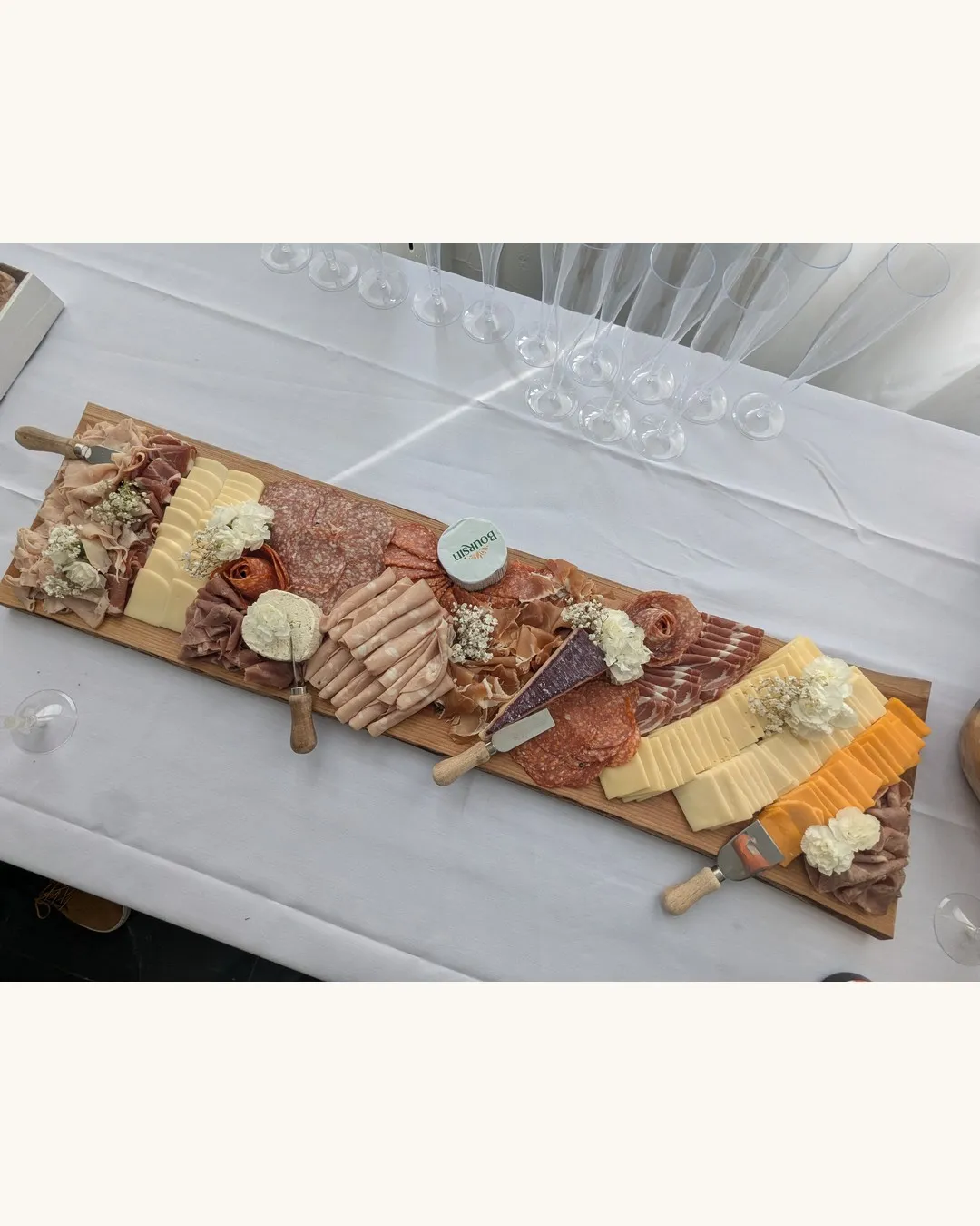 Long wooden grazing board of cured meats, cheeses and crackers