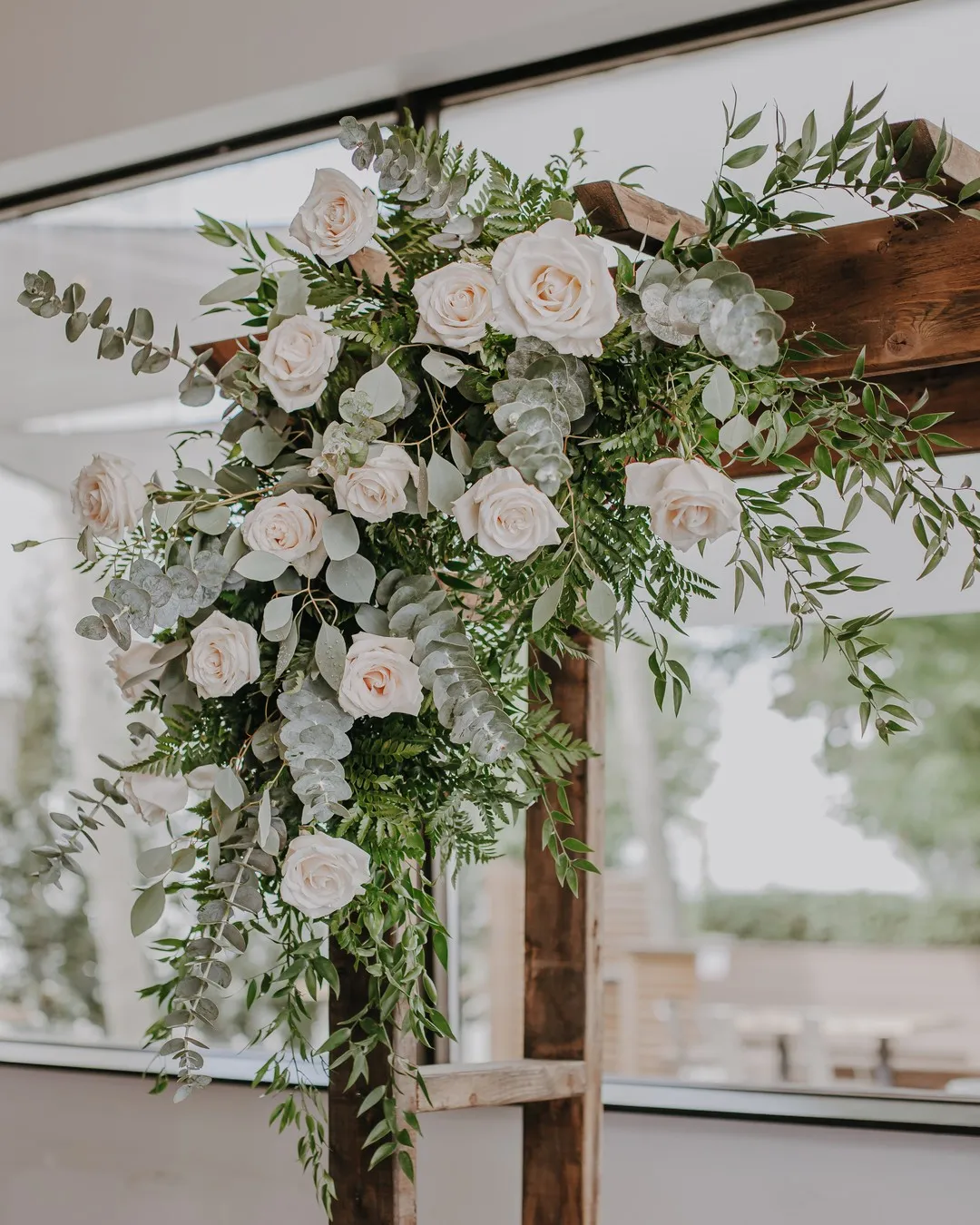 Wooden arbour with a corner spray of blush and white roses and trailing eucalyptus