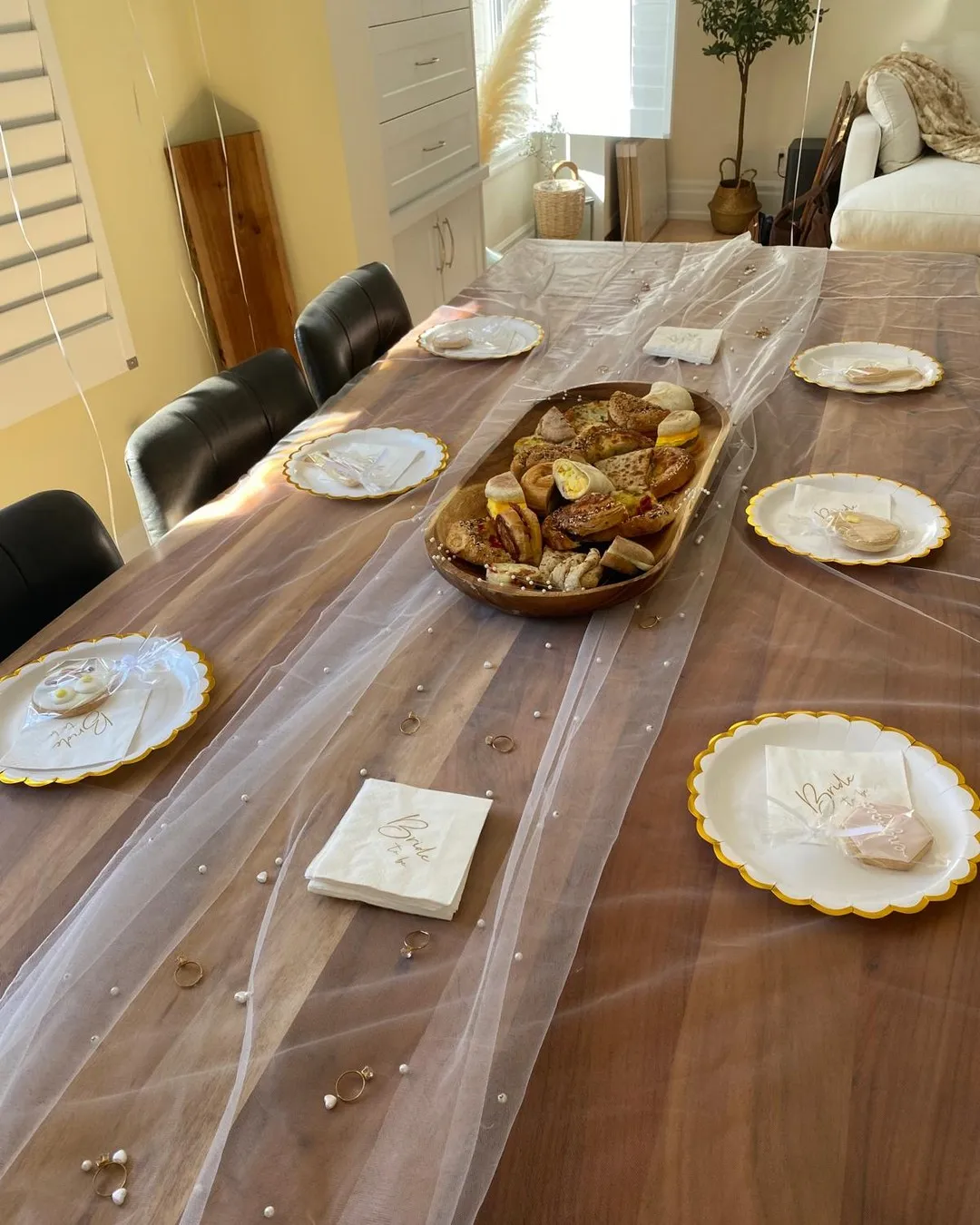 Long table with sheer tulle down the centre, gold-rimmed plates and scattered pearls