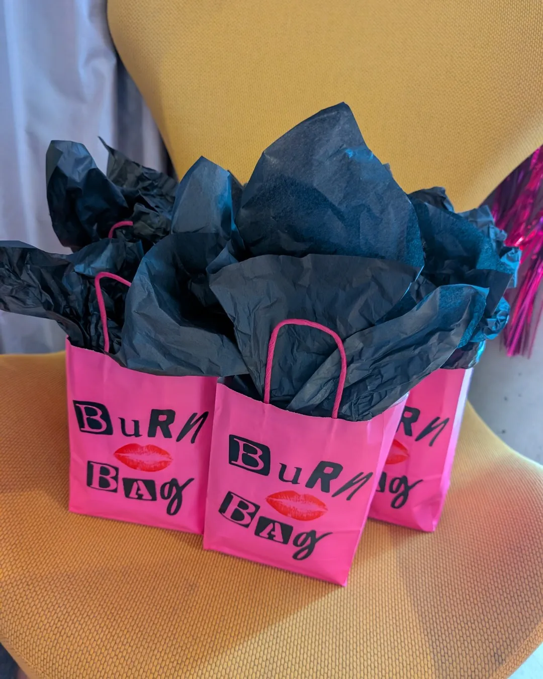 Hot-pink "Burn bag" gift bags stuffed with black tissue paper