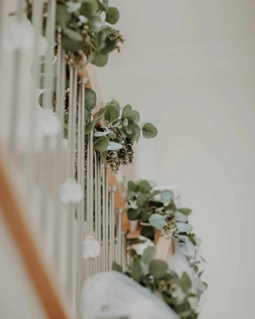 Staircase railing wrapped in eucalyptus garland with small white flowers