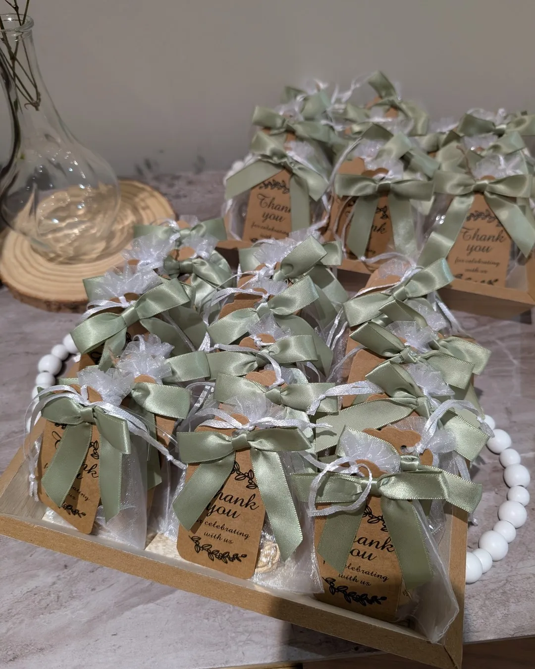 Favours wrapped in tulle and tied with sage ribbon and kraft thank-you tags