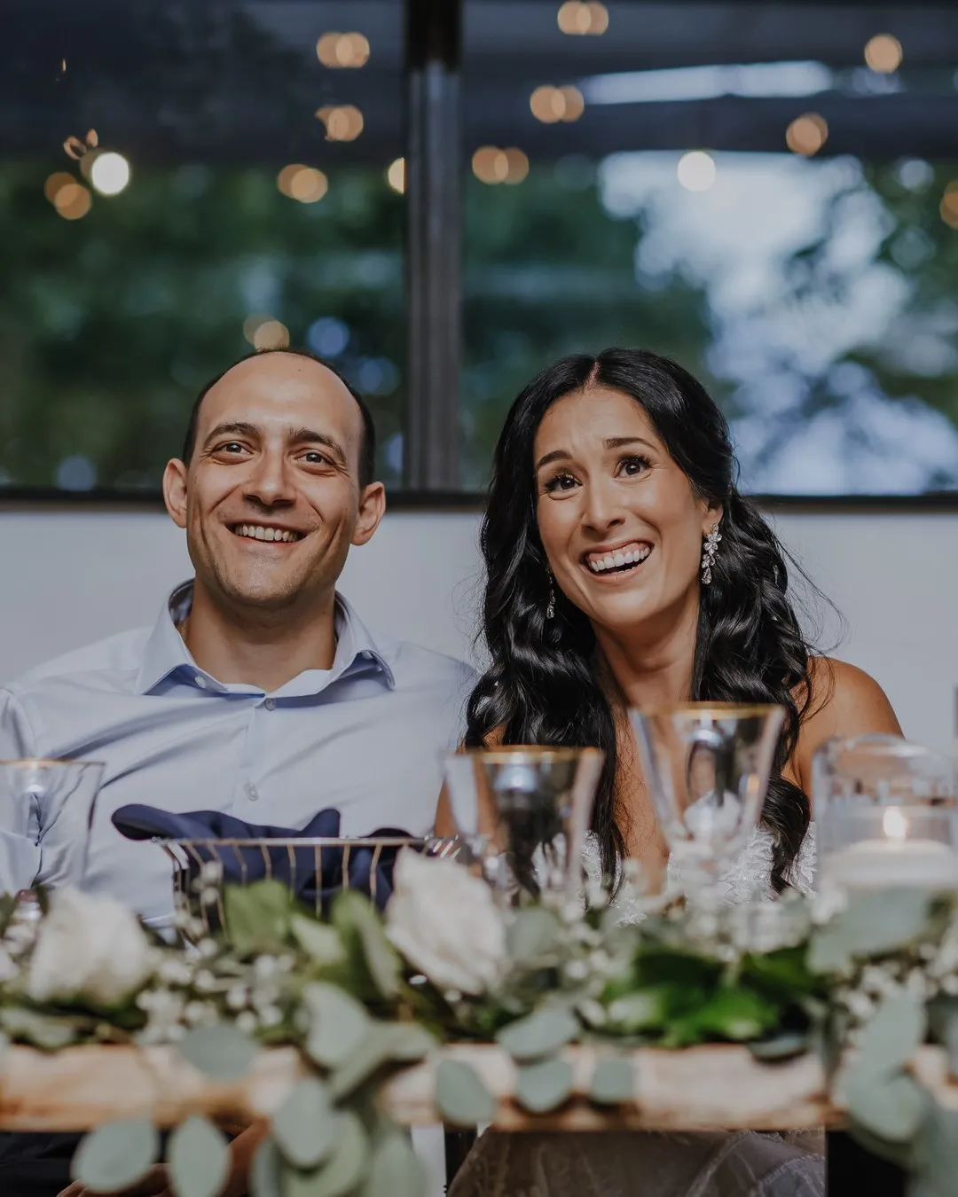 Sweetheart table garland of eucalyptus and white flowers, with the couple seated behind it